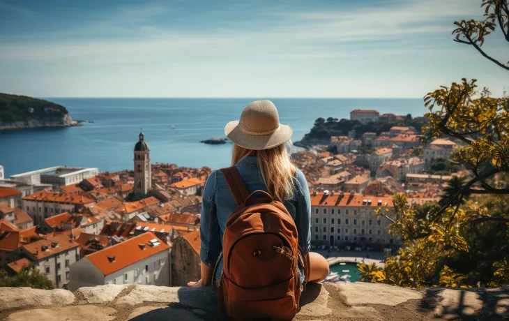 junge Frau mit Rucksack blickt auf Dubrovnik