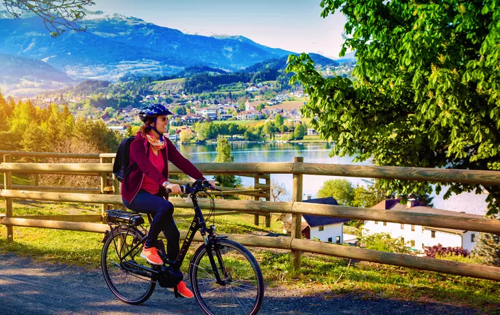 Frau mit E-Bike neben einem schönen See