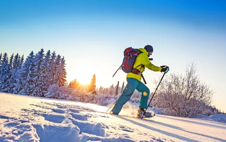 Sonnige Winterlandschaft mit Mann auf Schneeschuhen