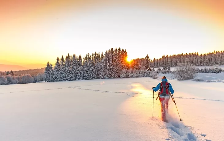 Sonnige Winterlandschaft mit Mann auf Schneeschuhen