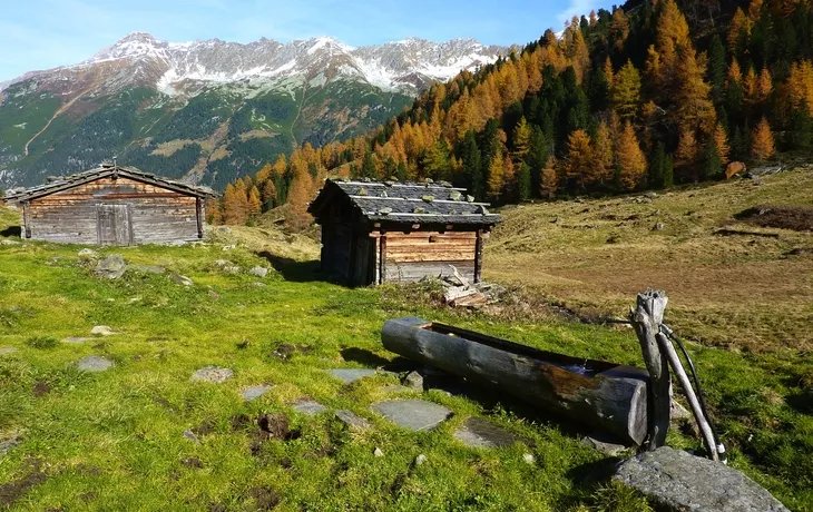 Almhütten mit Holzbrunnen im Herbst